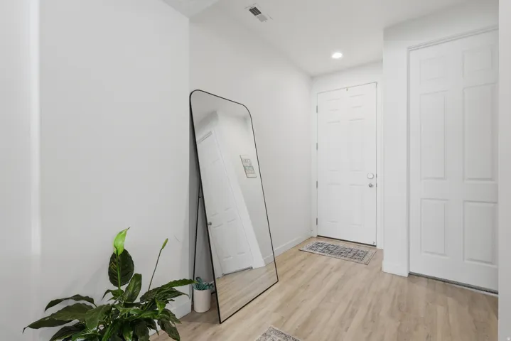 Light wood-finish flooring with white baseboards and white paneled doors