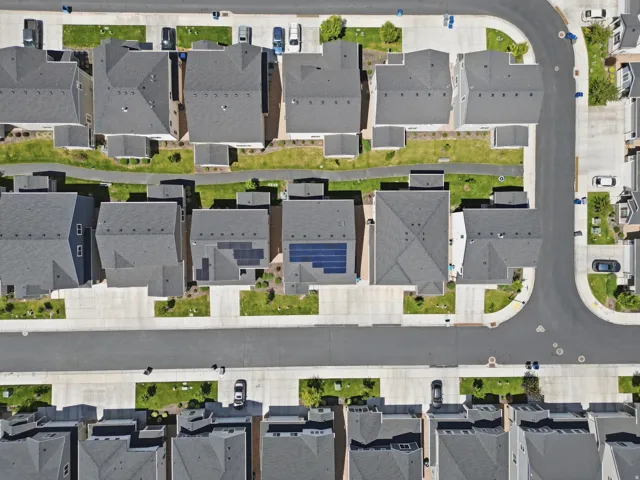 Aerial perspective showcasing a residential community with uniform gray-shingled rooftops