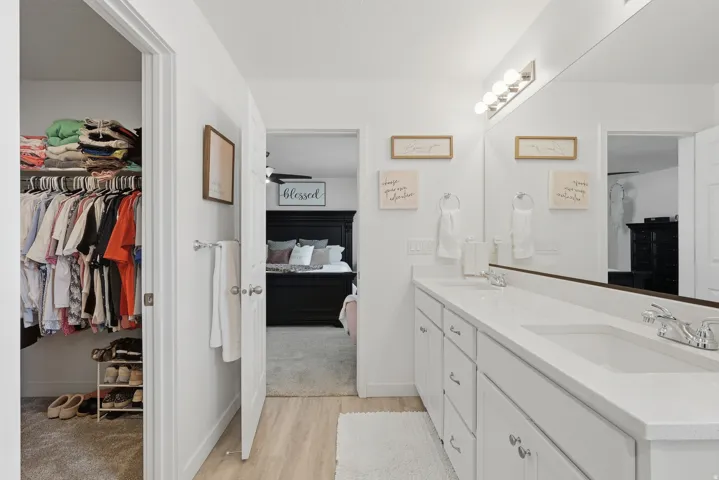 Double vanity with integrated sinks, white cabinetry, and polished chrome hardware