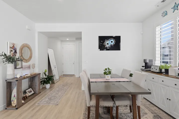 Open-concept room featuring wood-finish flooring, a dining area, and a white built-in console with a wood countertop