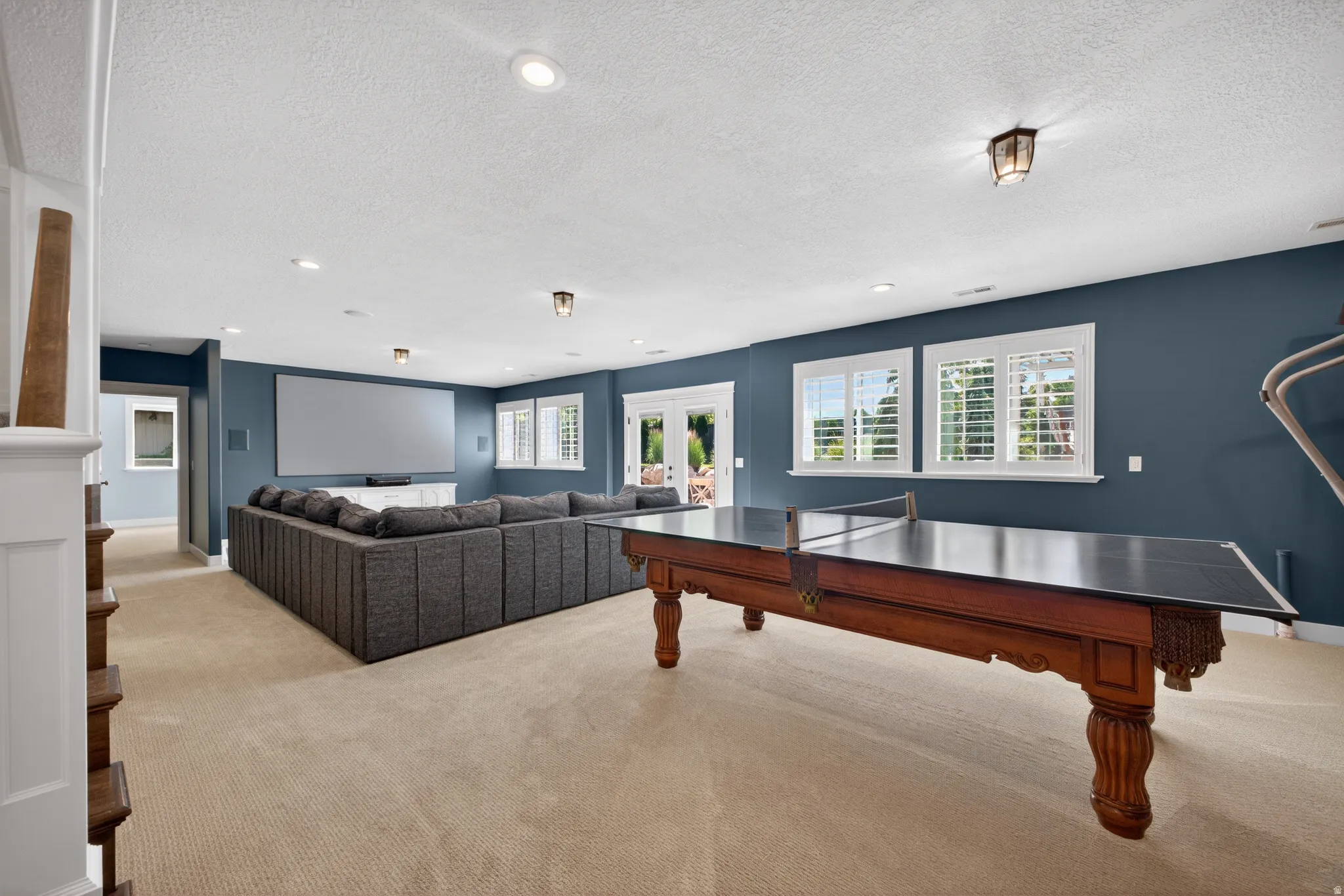 Spacious recreation room featuring recessed lighting, a large projection screen, and durable carpeting