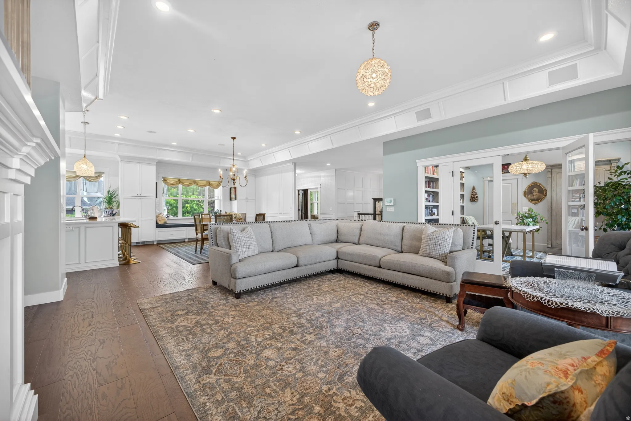 Open-concept living area featuring wood-finish flooring, recessed lighting, and ornate chandeliers