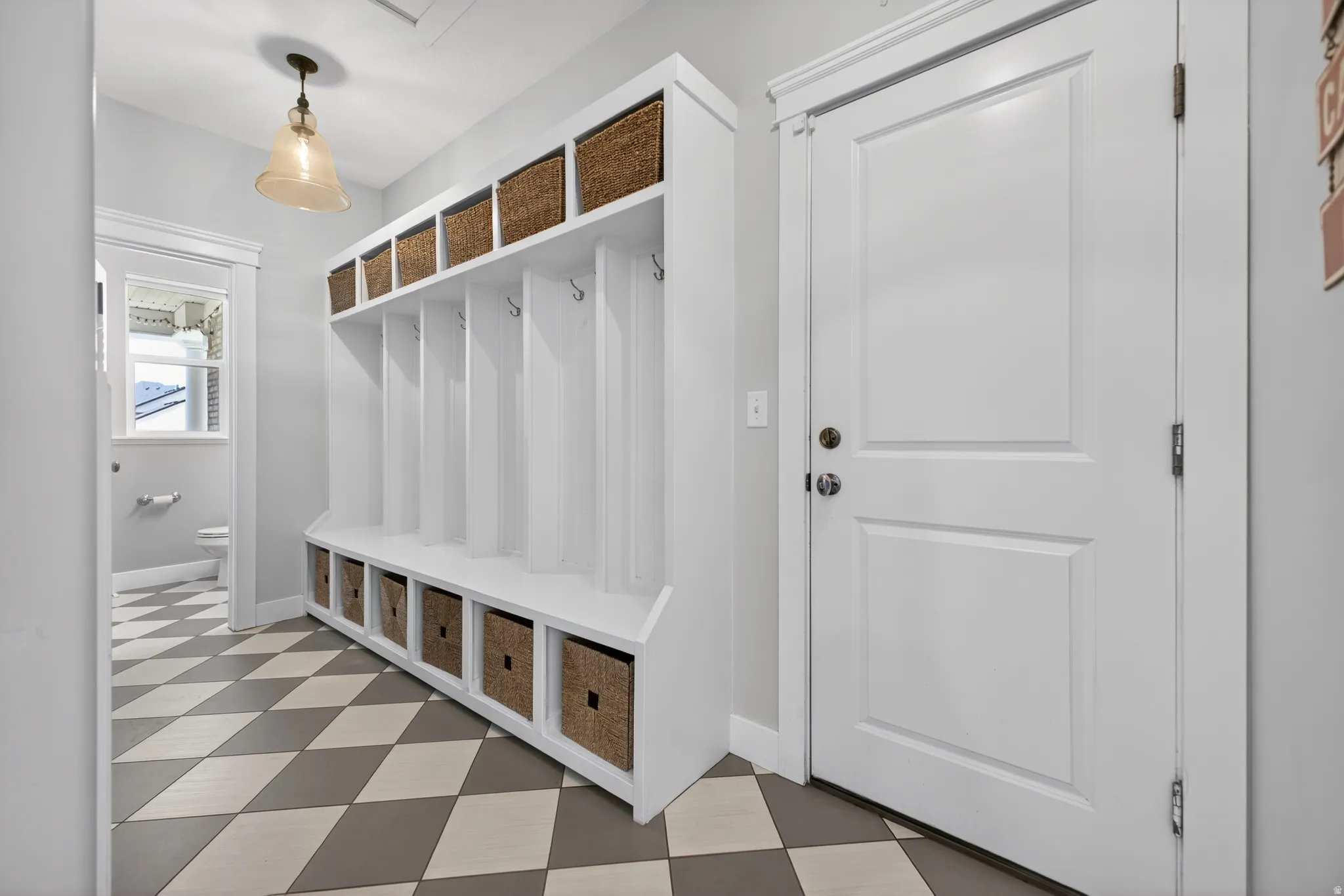 Custom built-in mudroom bench with cubbies and woven baskets provides ample storage