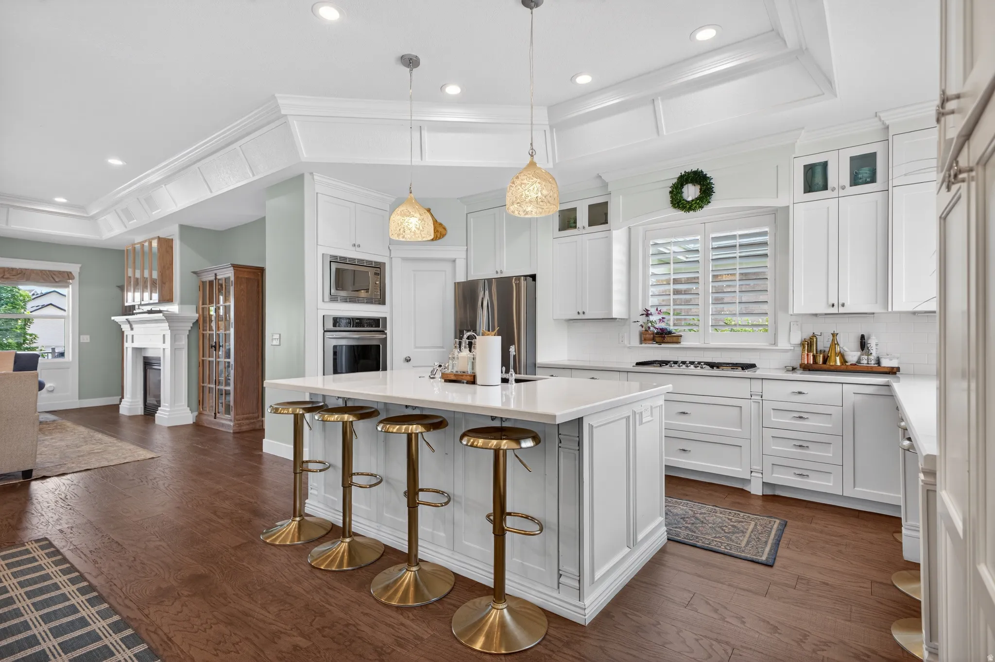 Gourmet kitchen featuring white cabinetry, stainless steel appliances, a large central island with seating, recessed lighting, and wood-finish flooring