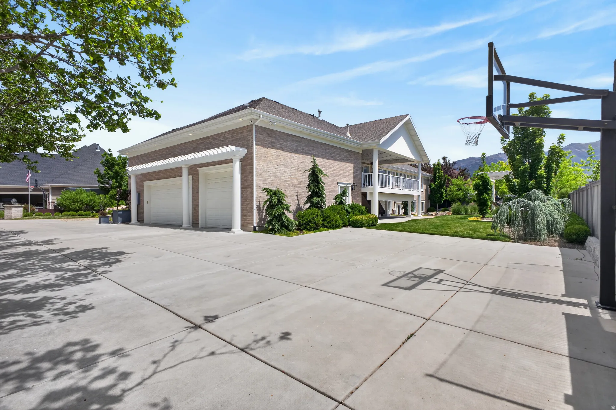 Expansive concrete driveway and two-car garage with pergola-style detailing