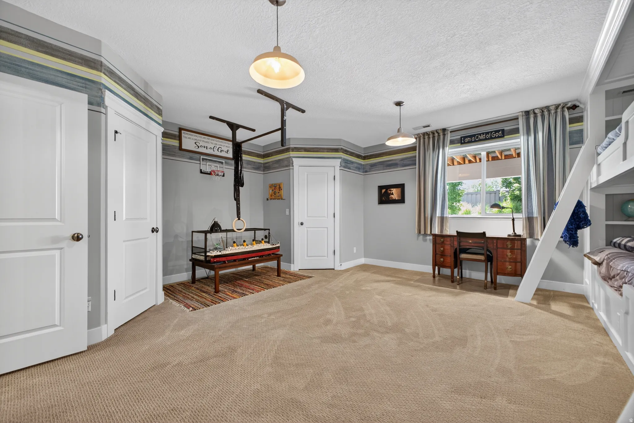 Spacious room featuring neutral carpeting and light gray walls with a decorative border