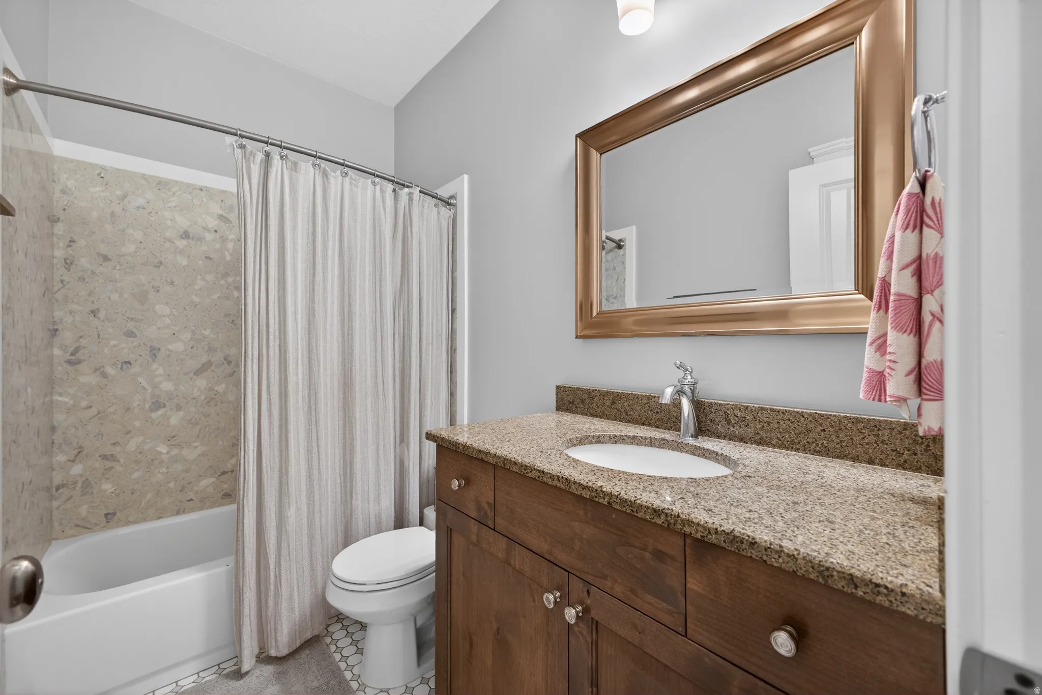 Bathroom featuring a wood-finish vanity with a stone countertop and an undermount sink