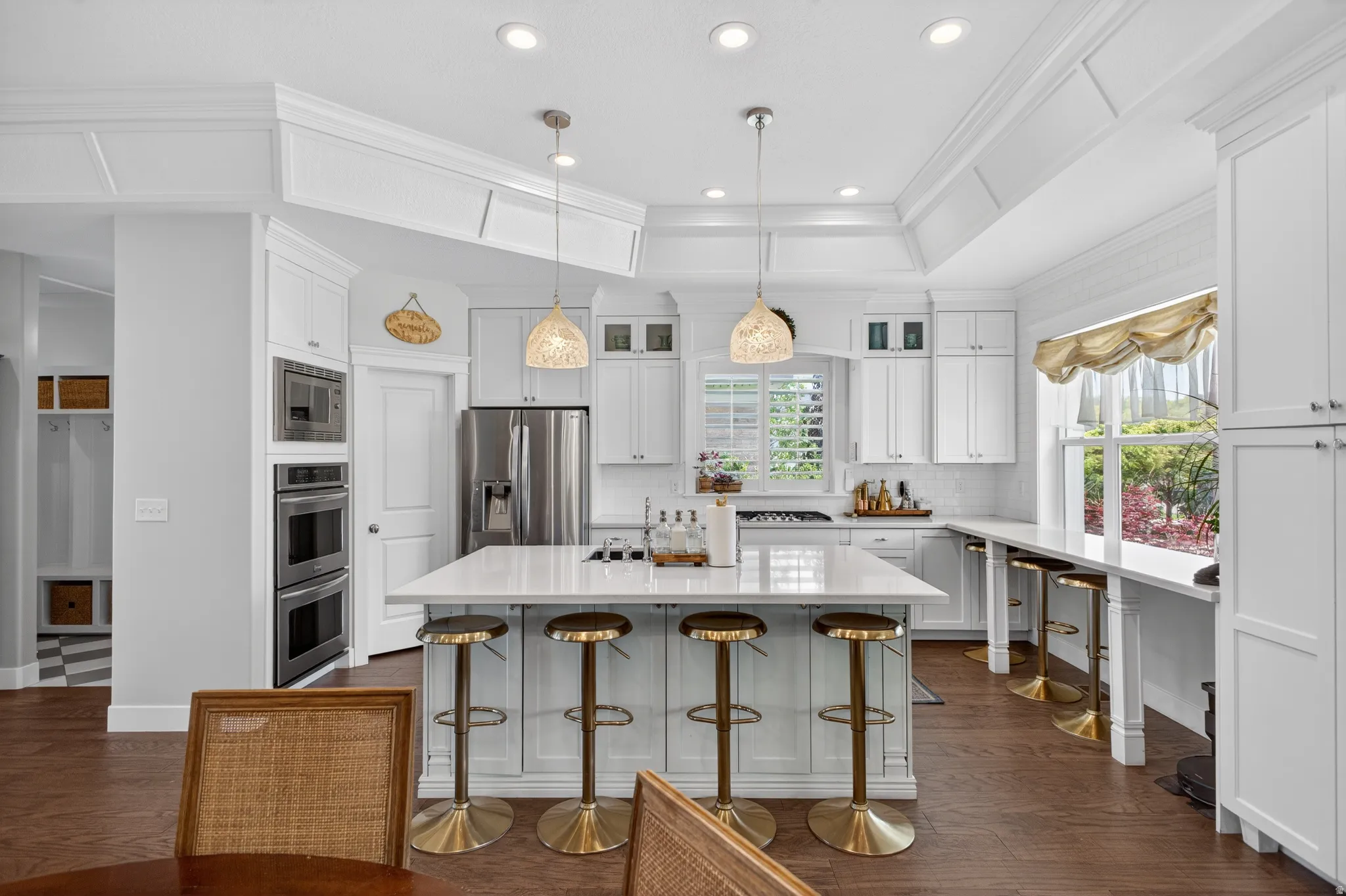 Bright kitchen featuring white cabinetry, a large center island with seating, stainless steel appliances, and wood-finish flooring