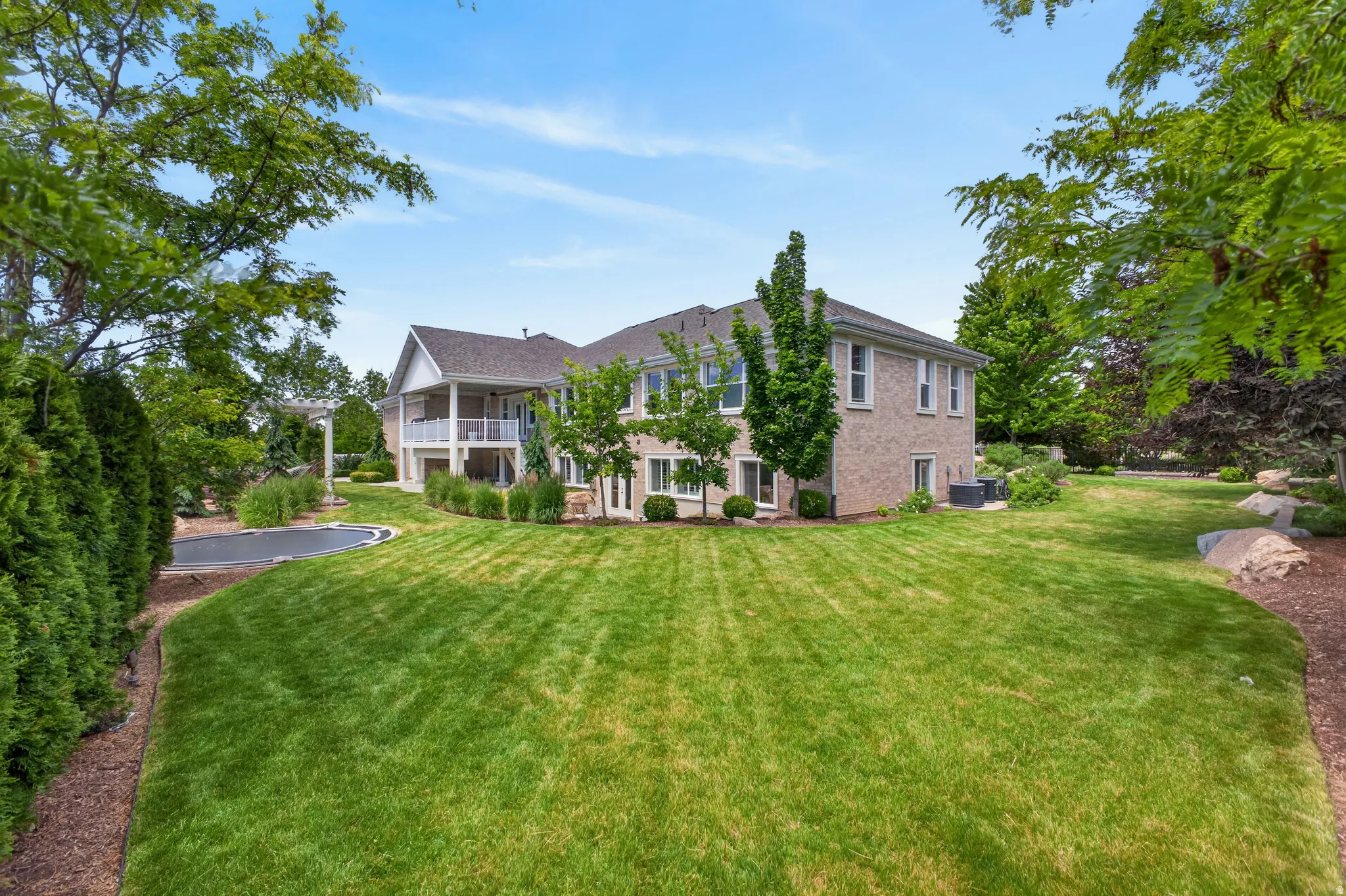 Expansive backyard featuring a manicured lawn and mature trees