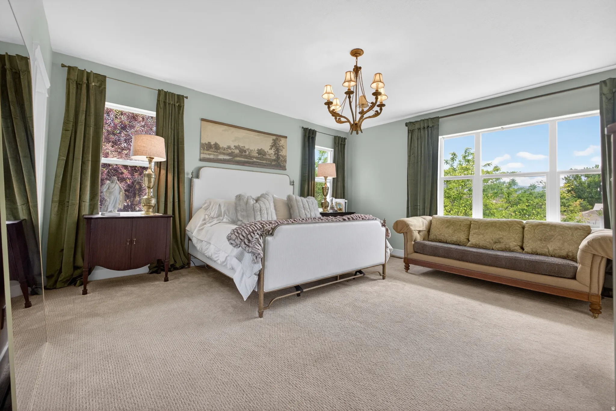Spacious room featuring broadloom carpeting, light blue wall paint, and a multi-pane window overlooking trees