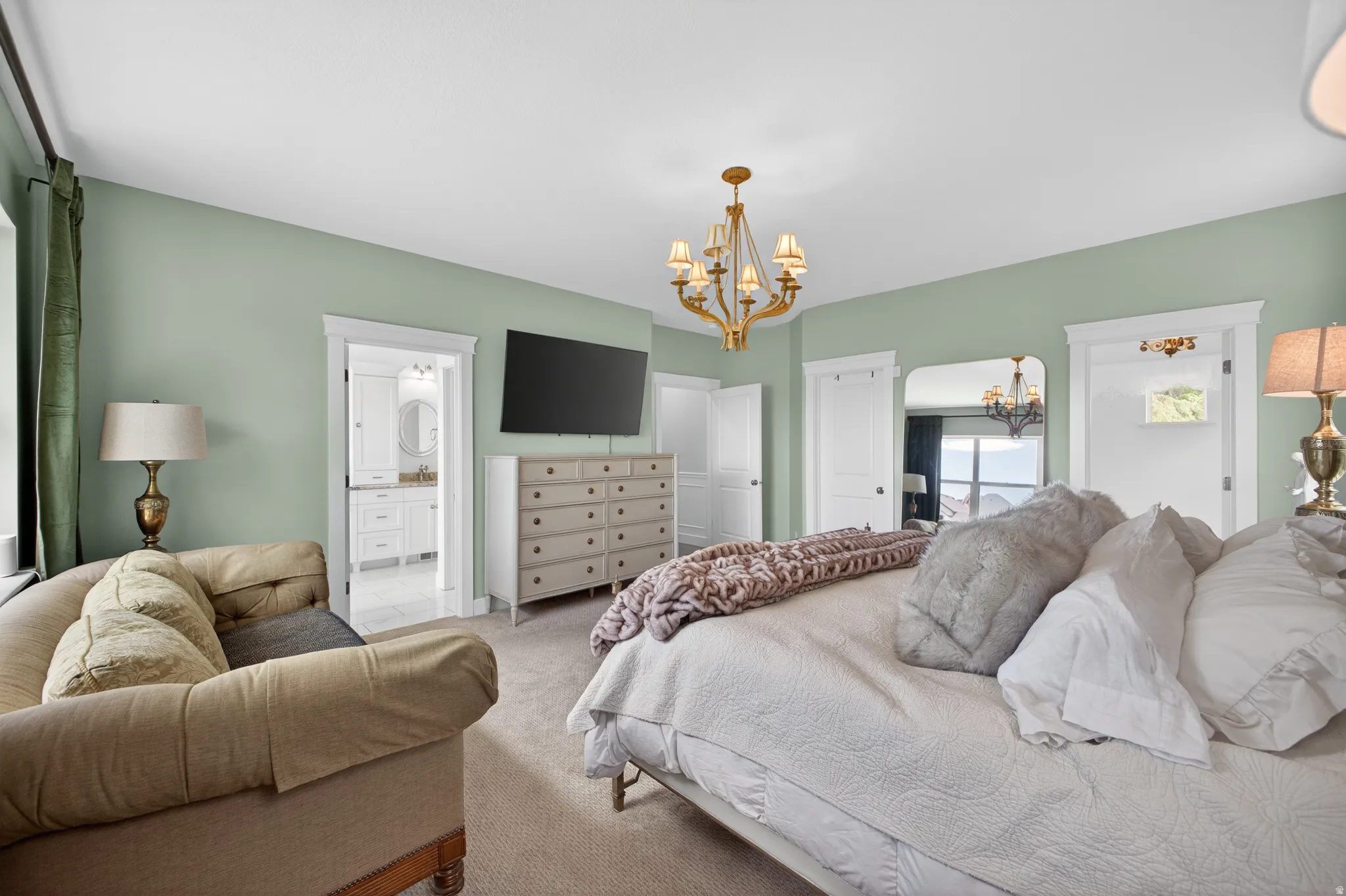 Spacious bedroom featuring light green walls, white trim, and a gold-finish chandelier