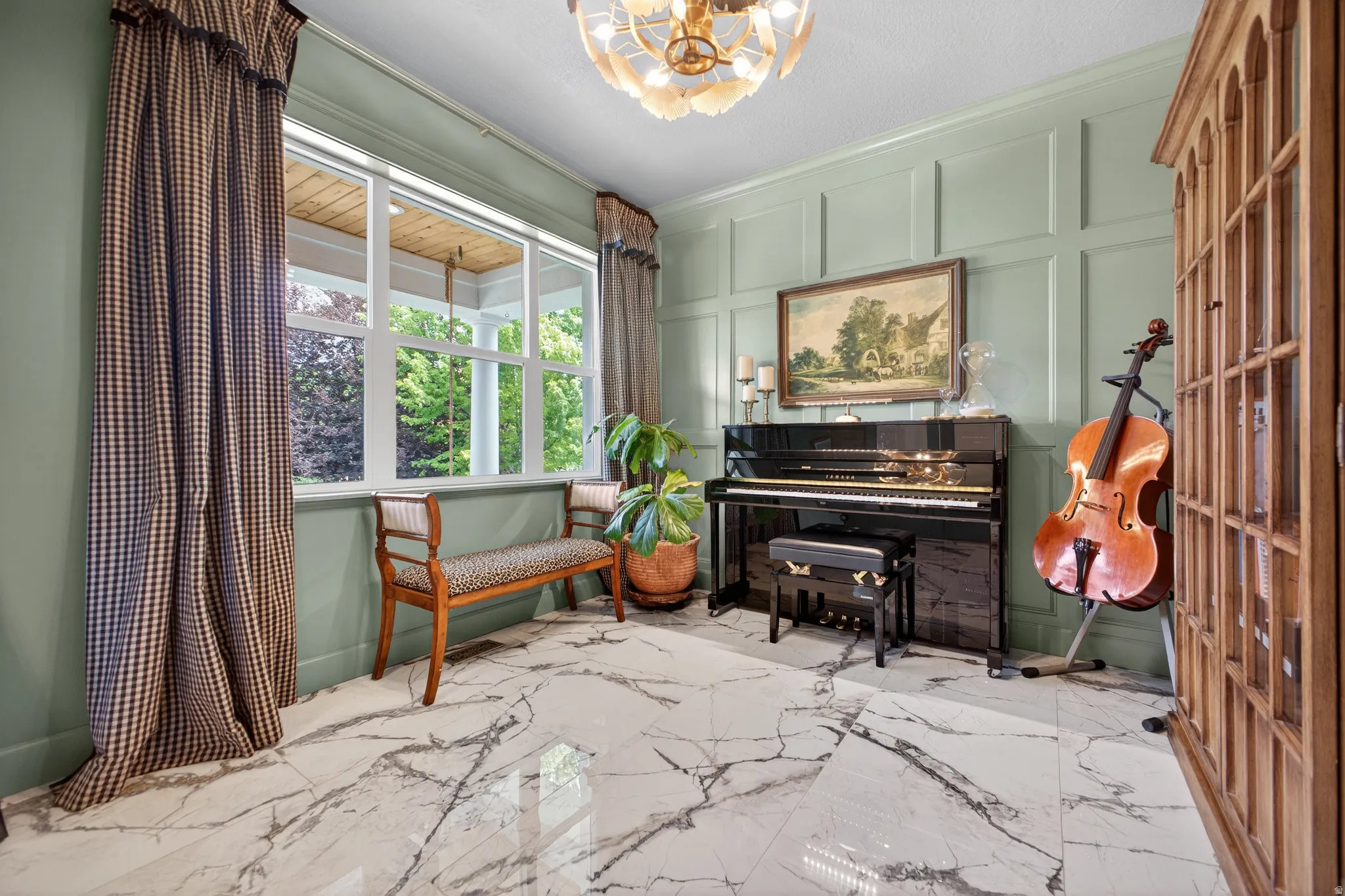 Room featuring large windows, a decorative chandelier, wainscoting paneling, and polished marble-look flooring