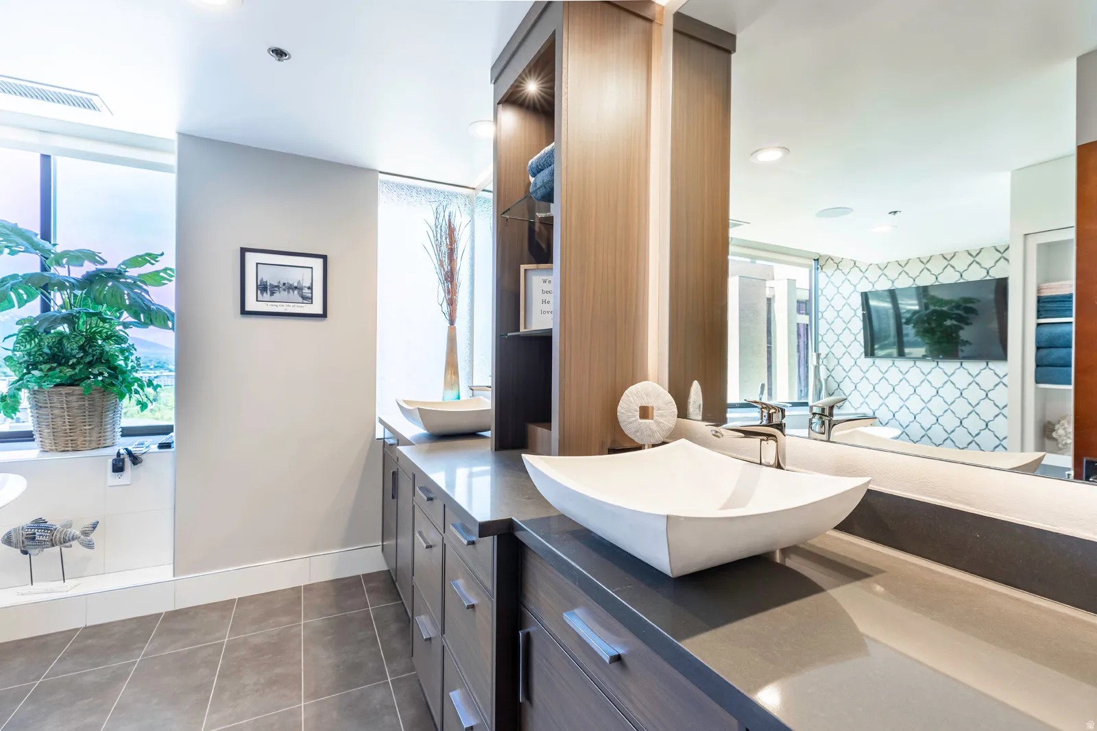 Dual vessel sinks set atop a broad countertop with extensive cabinetry
