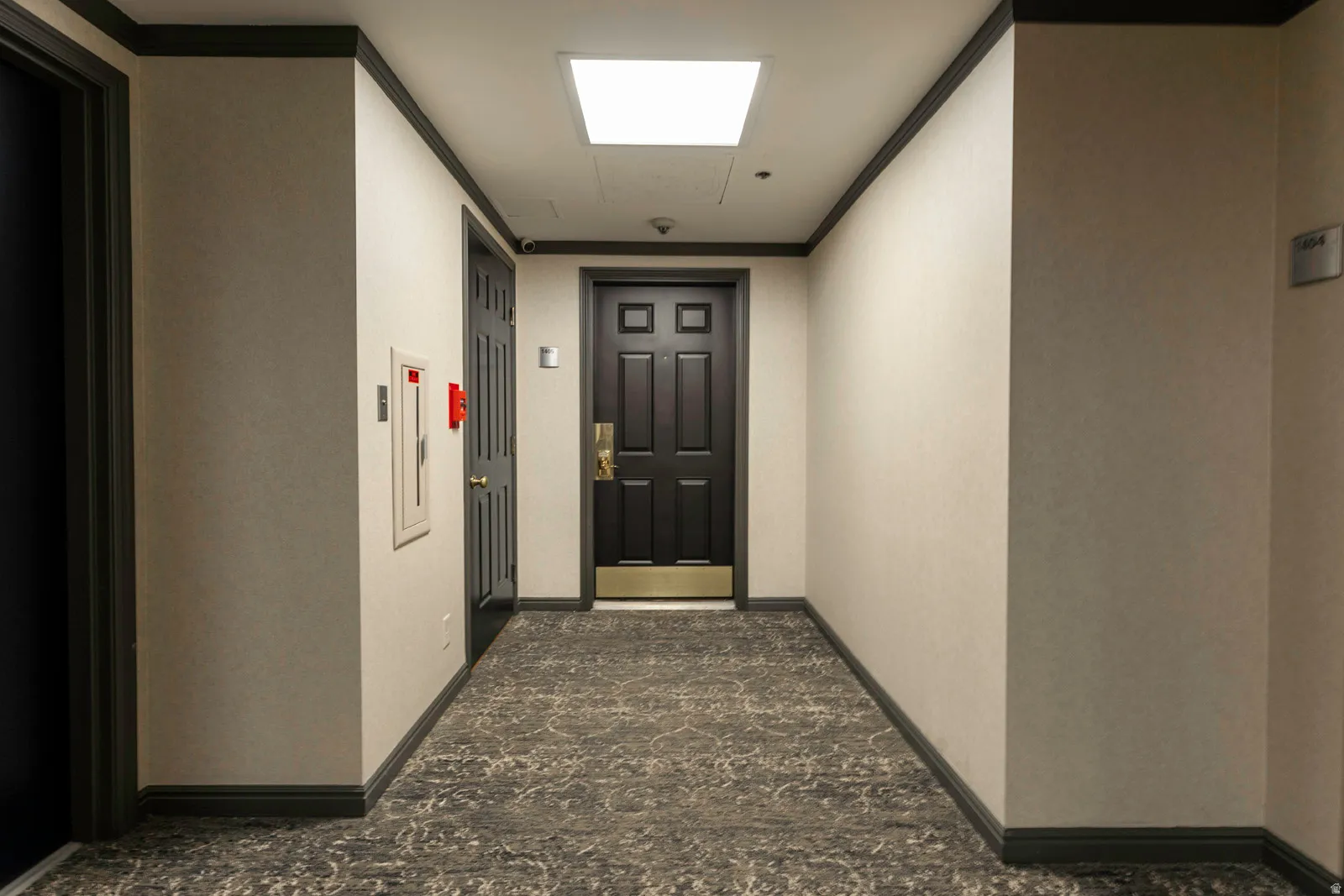 Hallway with patterned carpet flooring, light-toned walls, dark trim, and a recessed ceiling light