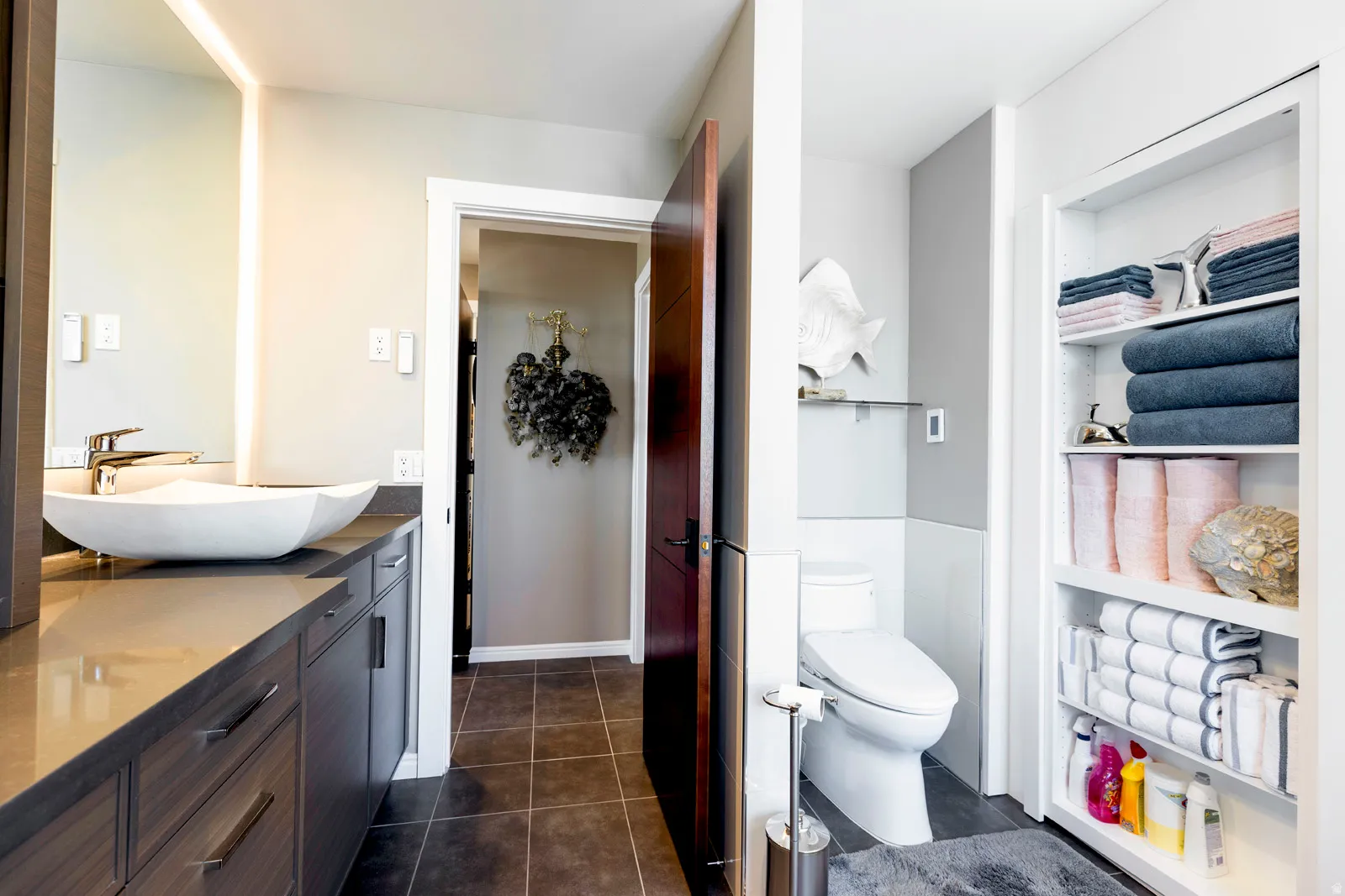 Modern vanity featuring a vessel sink, integrated countertop, and ample storage cabinetry