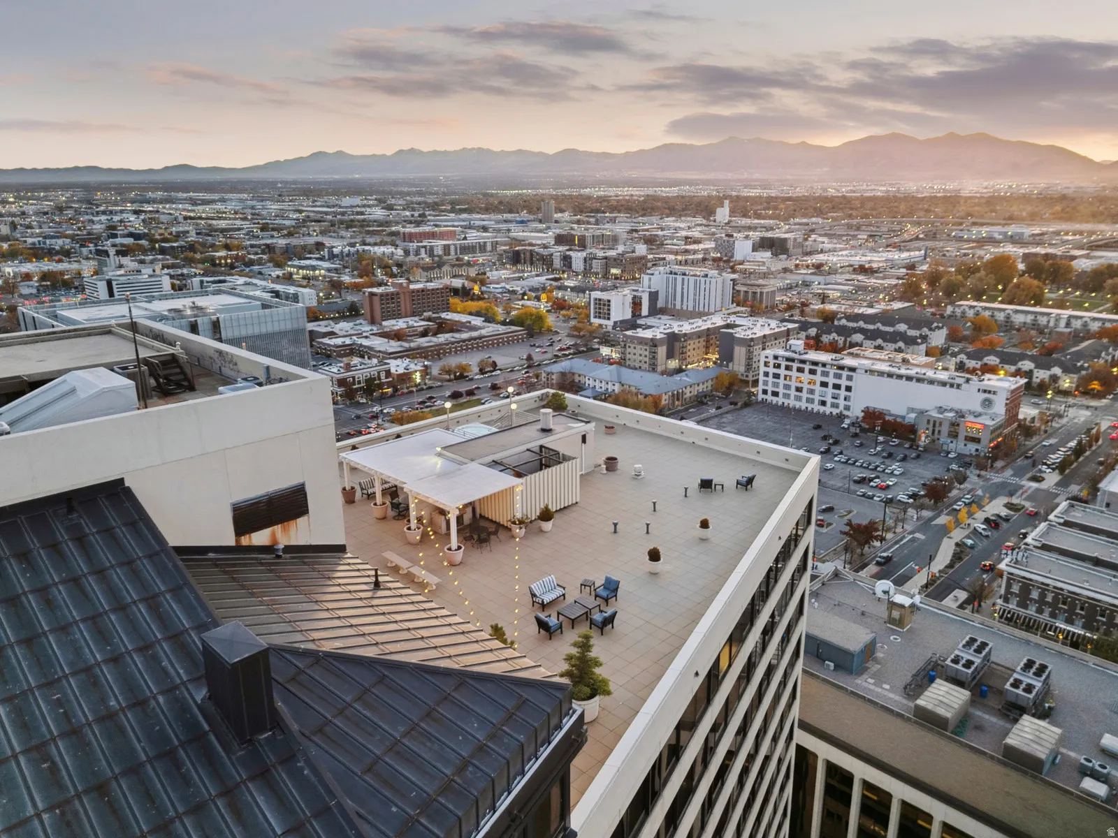 Rooftop terrace featuring a pergola, string lighting, and city skyline