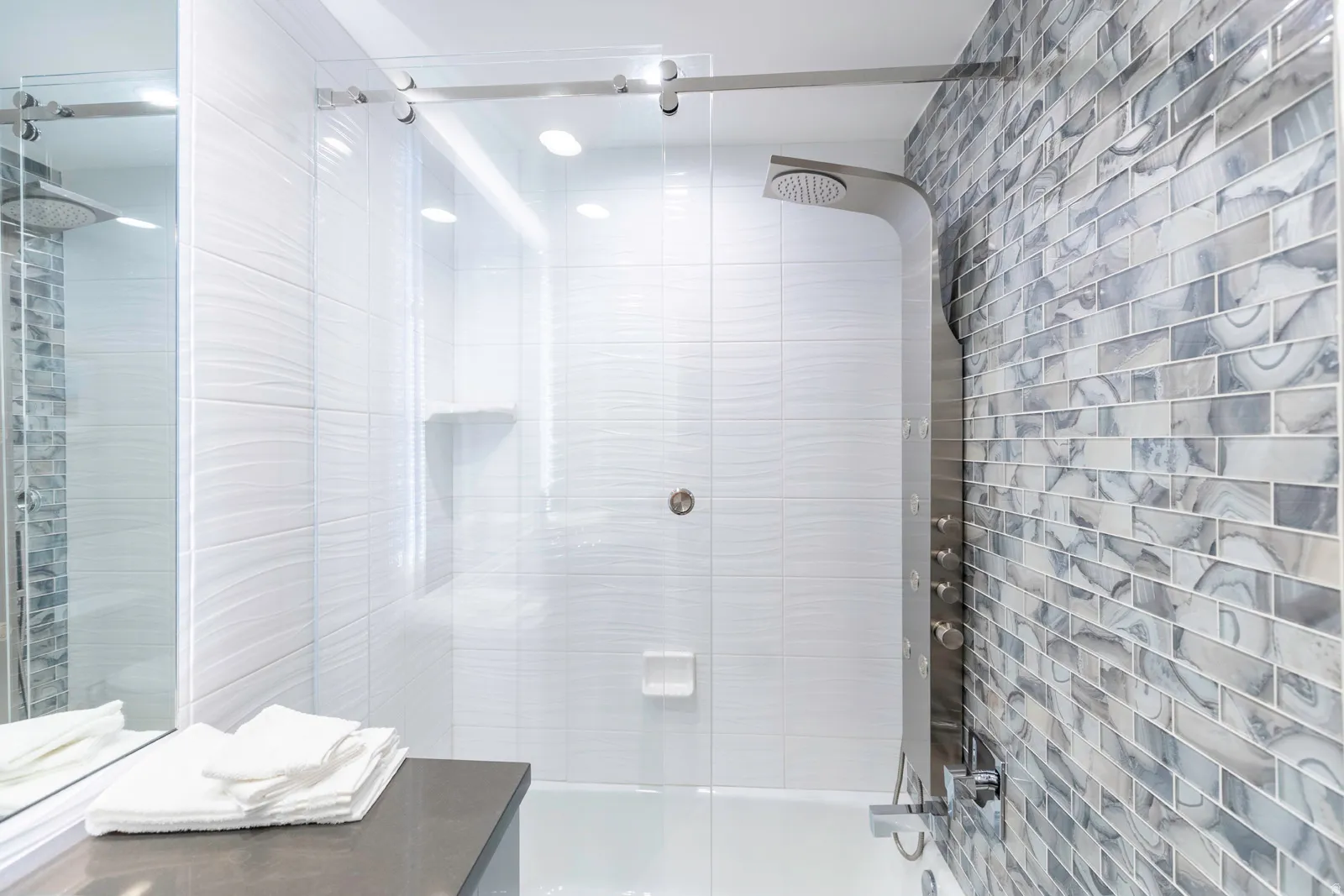 Sleek glass-enclosed shower with a multi-function shower panel
