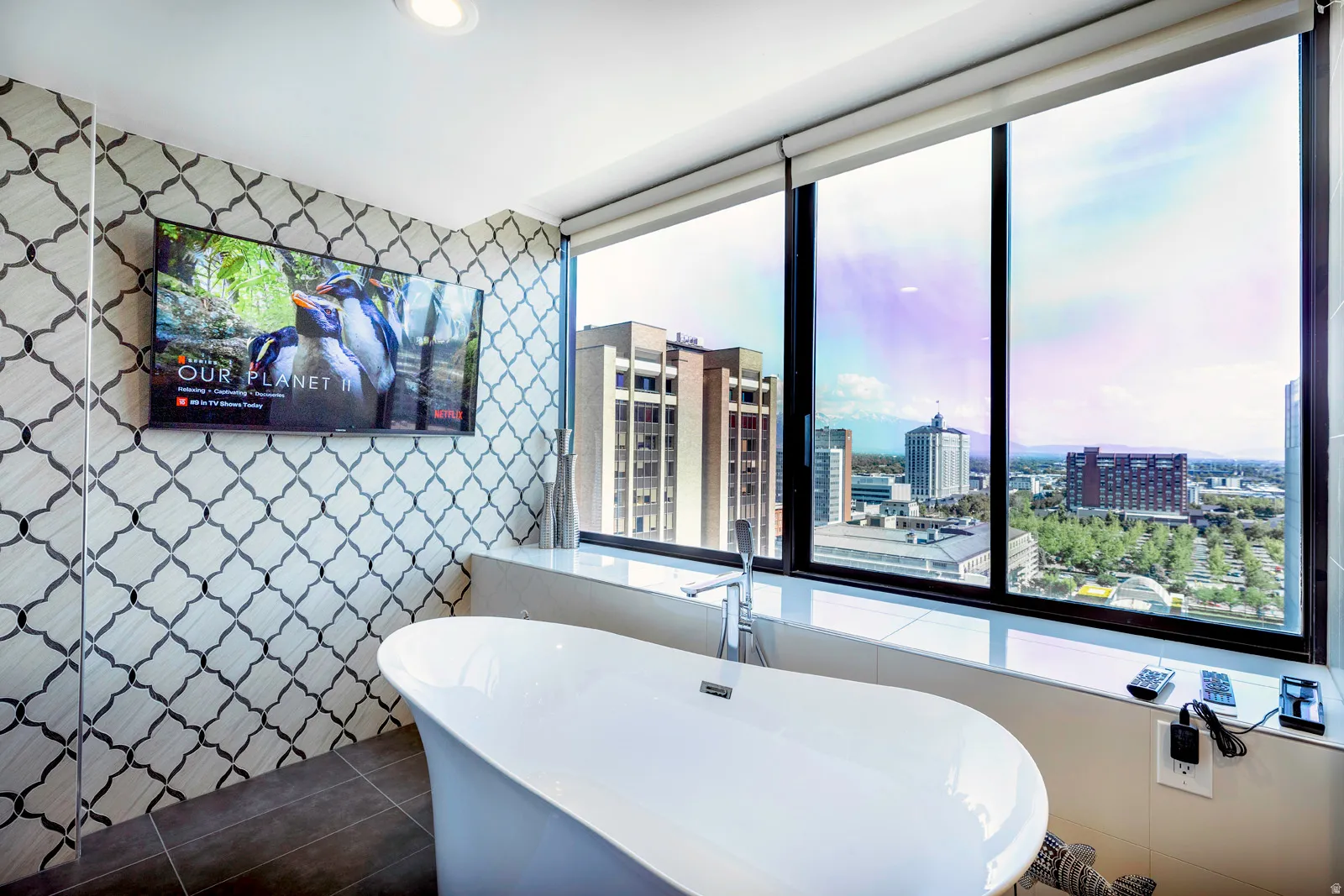 Freestanding soaking tub with a floor-mounted faucet, complemented by a full-height decorative tile accent wall
