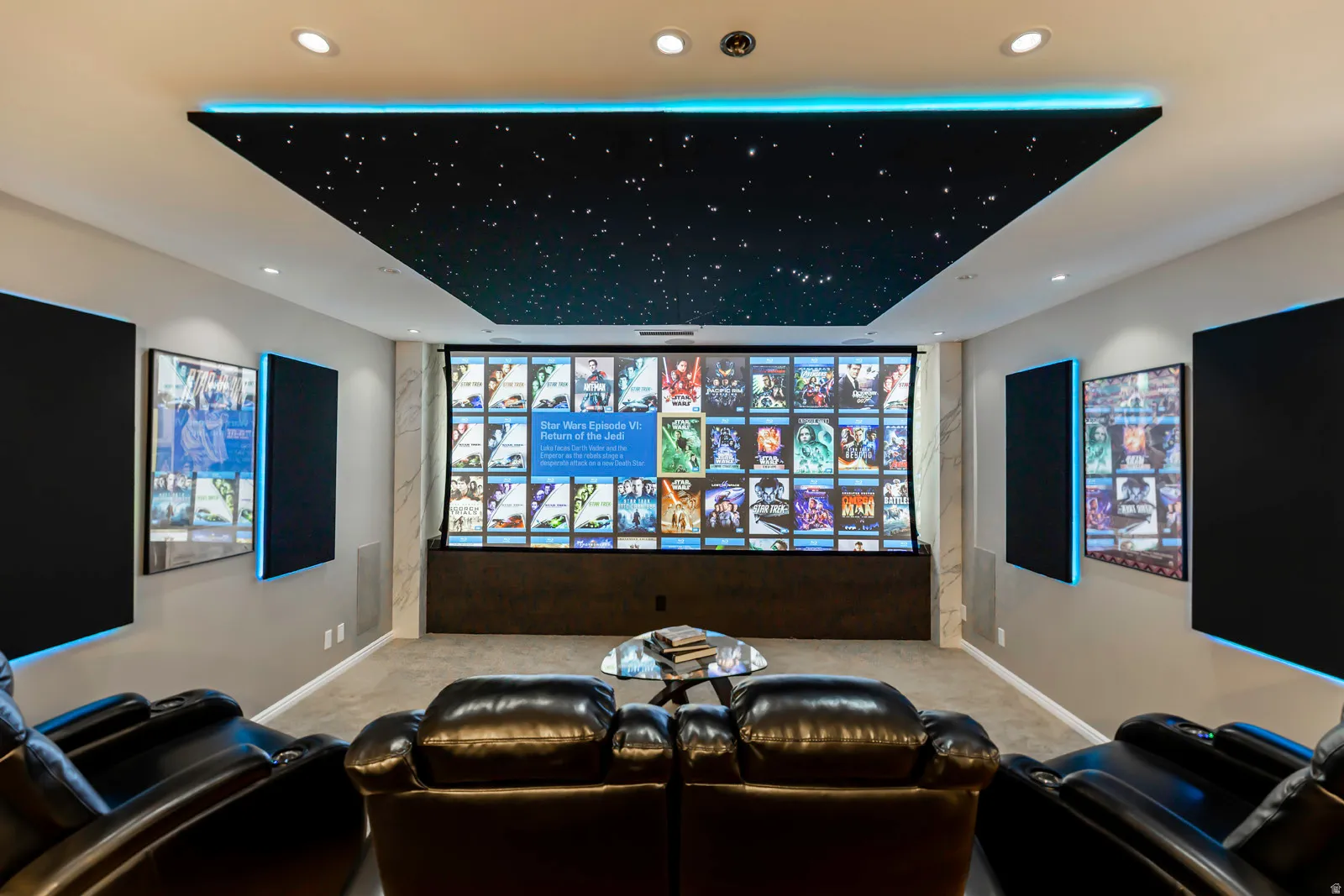 Dedicated media room featuring a starry night ceiling panel with accent lighting, large projection screen, recessed lighting, and wall-mounted acoustic panels with perimeter illumination