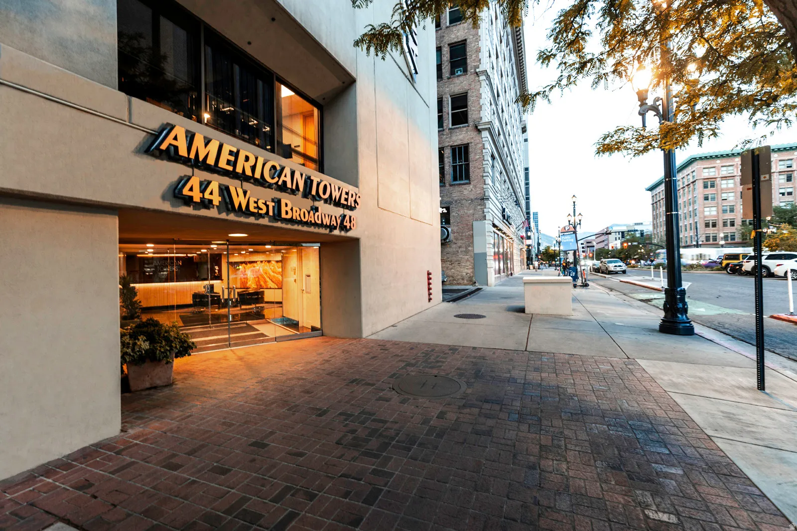 American Towers building entrance with prominent signage, a glass door entry, and a textured brick paver walkway