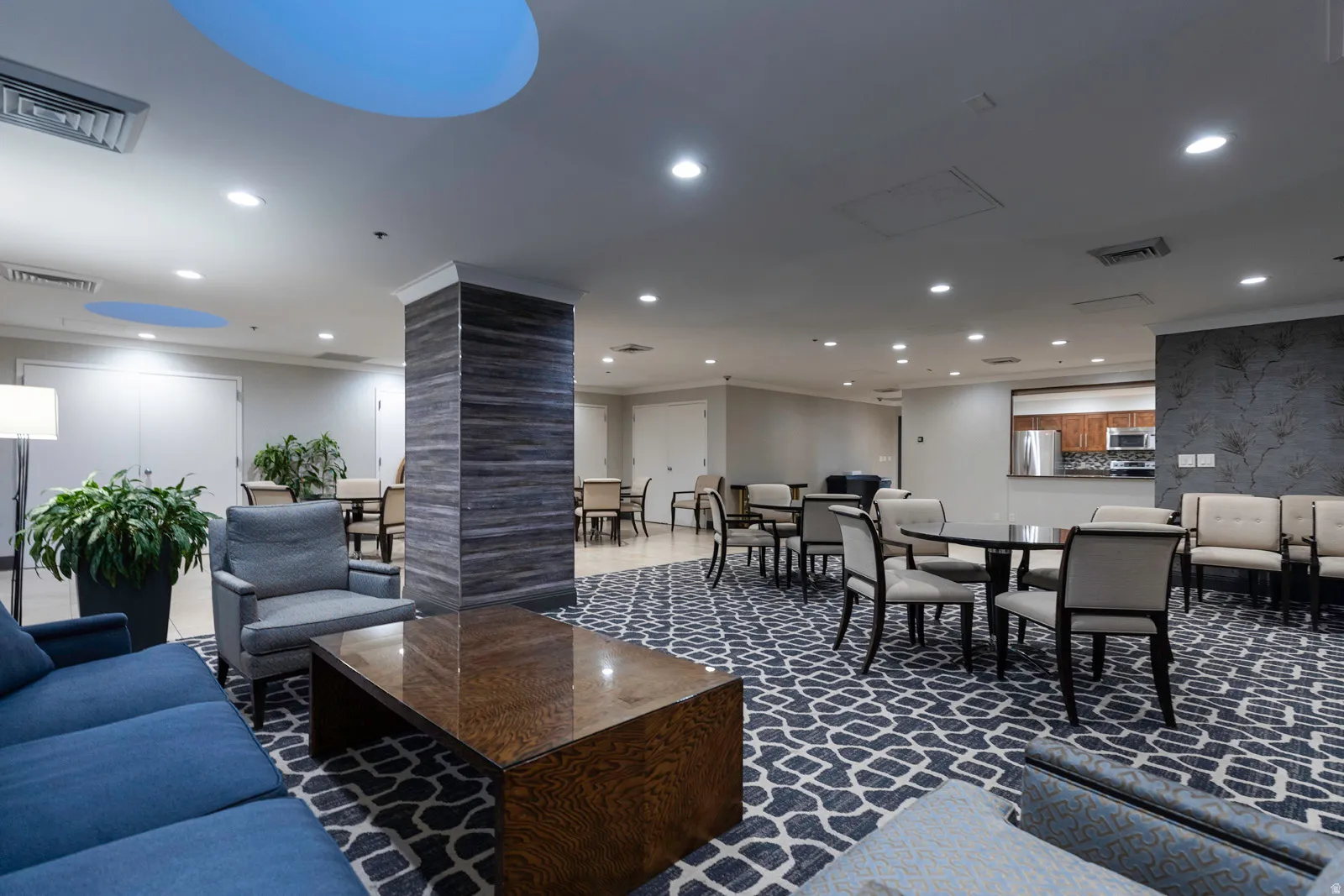 Spacious common area featuring patterned carpeting, recessed lighting, and a textured accent wall