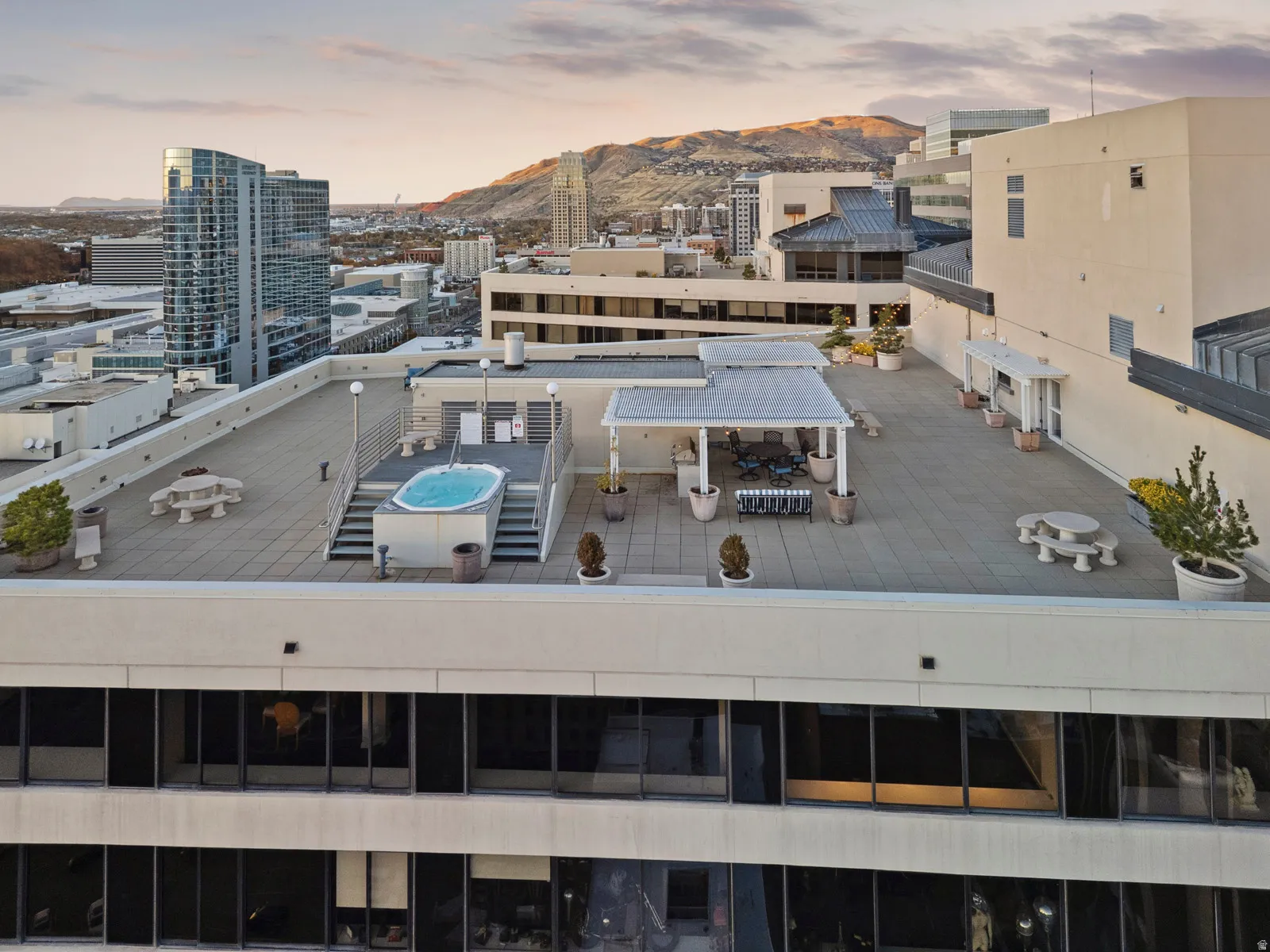 Rooftop patio with a built-in spa, shaded dining area, multiple seating arrangements, and large planters