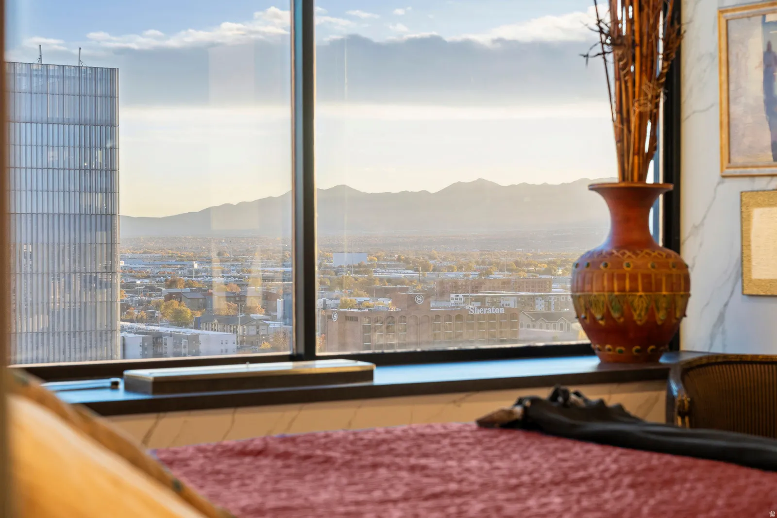Floor-to-ceiling windows with a dark frame, a deep window sill, and a dark-toned wall featuring framed art