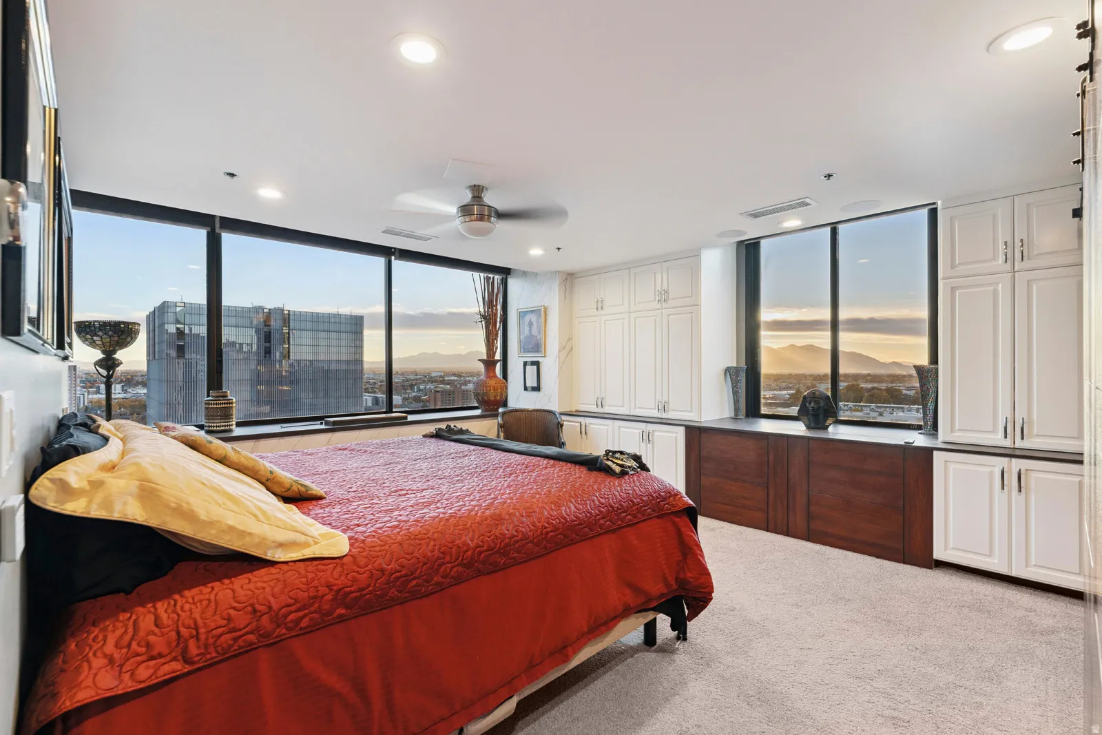 Expansive window wall with city and mountain scenery, complemented by integrated cabinetry featuring white upper units and dark wood lower units