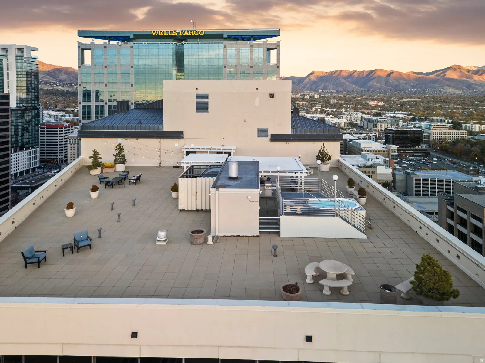 Expansive rooftop terrace featuring a tiled surface, a built-in hot tub, and multiple seating areas