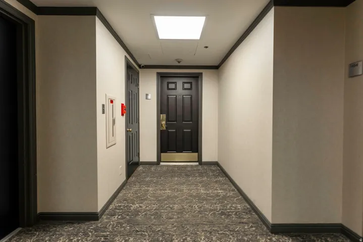 Hallway with patterned carpet flooring, light-toned walls, dark trim, and a recessed ceiling light