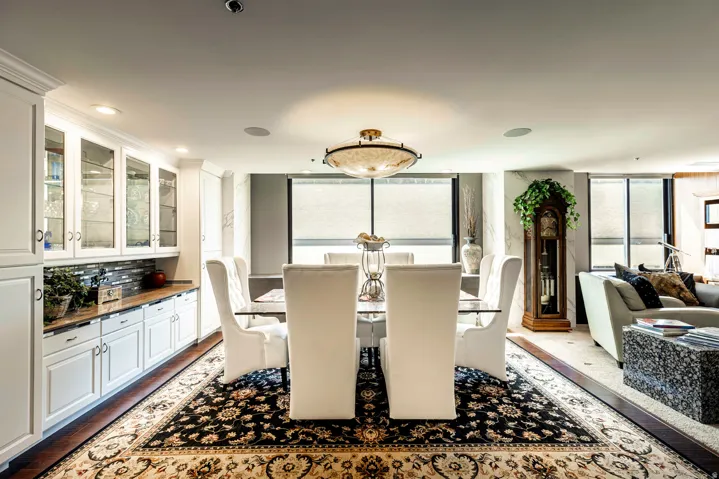 Dining area featuring a decorative ceiling light fixture, built-in cabinetry with glass-front uppers, a patterned area rug, and wood-finish flooring