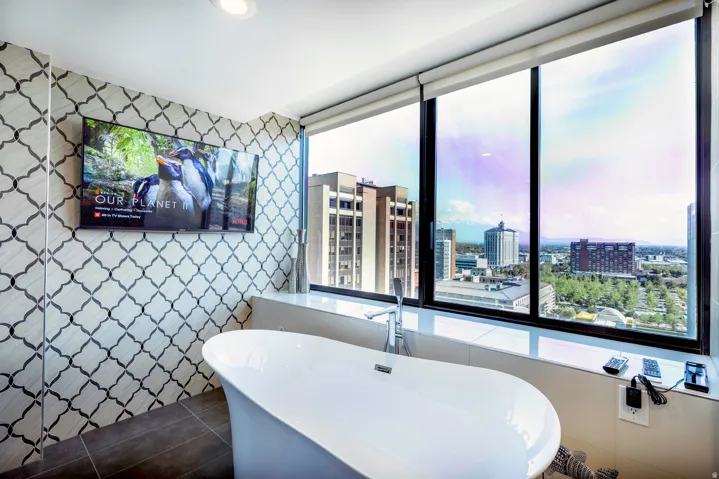 Freestanding soaking tub with a floor-mounted faucet, complemented by a full-height decorative tile accent wall