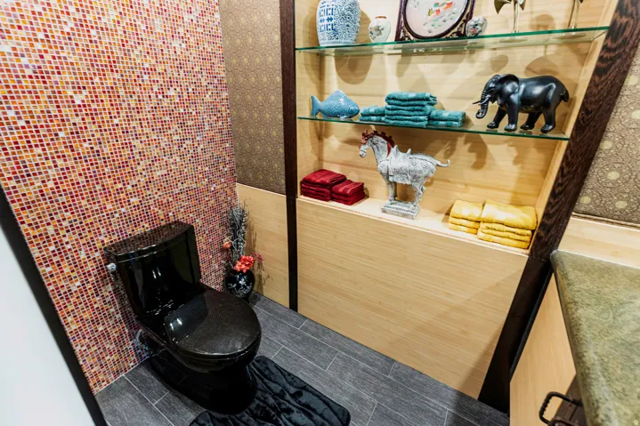 Powder room featuring a black toilet, mosaic tile accent wall, wood-finish flooring, and built-in shelving with glass shelves
