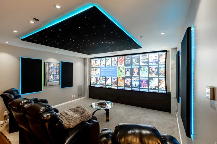 Dedicated media room featuring a large projection screen, recessed ceiling lighting, and a starfield ceiling with perimeter accent lighting