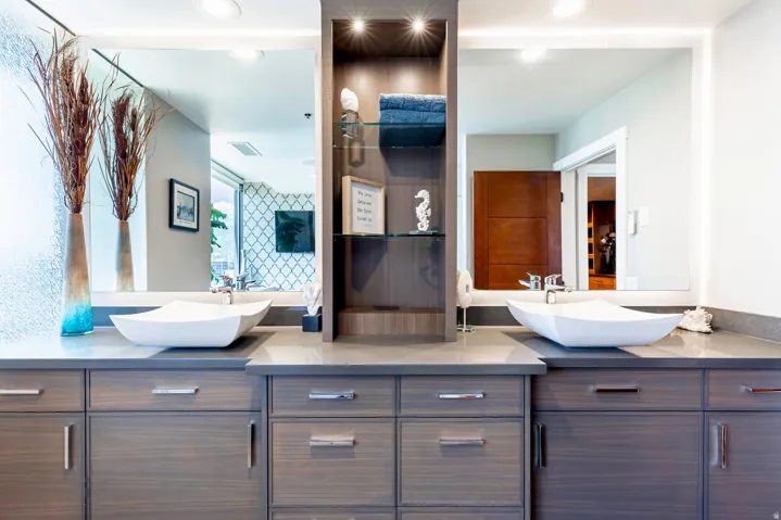 Dual vanity with wood-finish cabinetry, under-mount lighting, and integrated vessel sinks