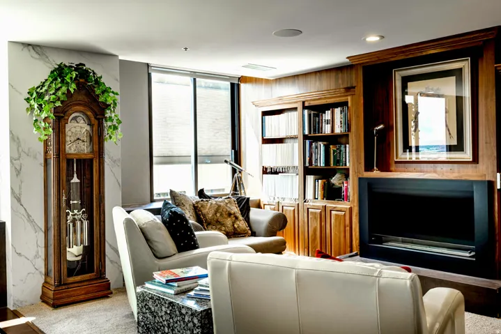 Living area featuring a floor-to-ceiling window, recessed ceiling lighting, a built-in wood-paneled entertainment center with shelving and an integrated fireplace, and a light-colored carpet