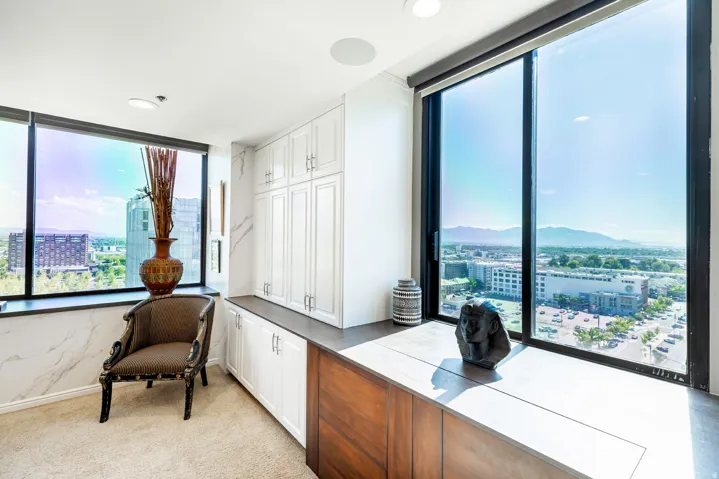Expansive floor-to-ceiling windows frame the cityscape and distant mountains