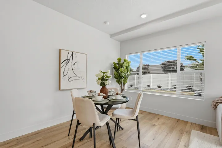 Recessed ceiling lighting illuminates a dining area featuring wood-finish flooring