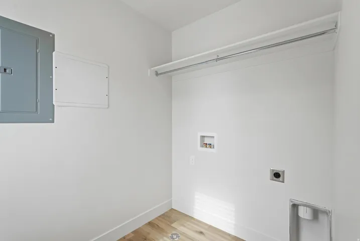 Dedicated laundry area featuring wood-finish flooring, white walls, and a built-in hanging rod