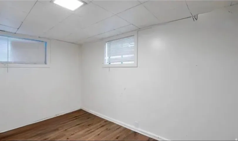 Room featuring wood-finish flooring, white walls, and two windows with blinds