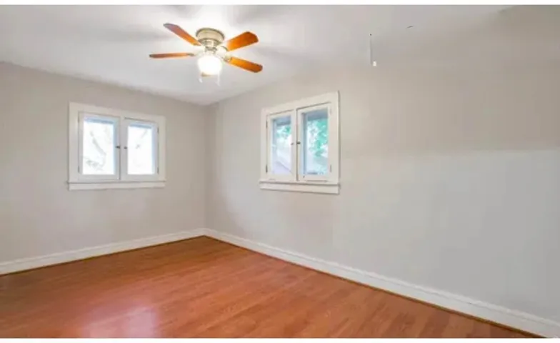 Spacious room with wood-finish flooring, light grey walls, and white trim