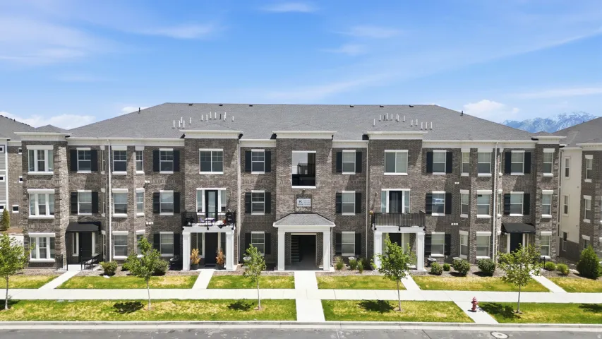 Multi-story brick facade building featuring a central portico entrance, multiple balconies, and dark window shutters
