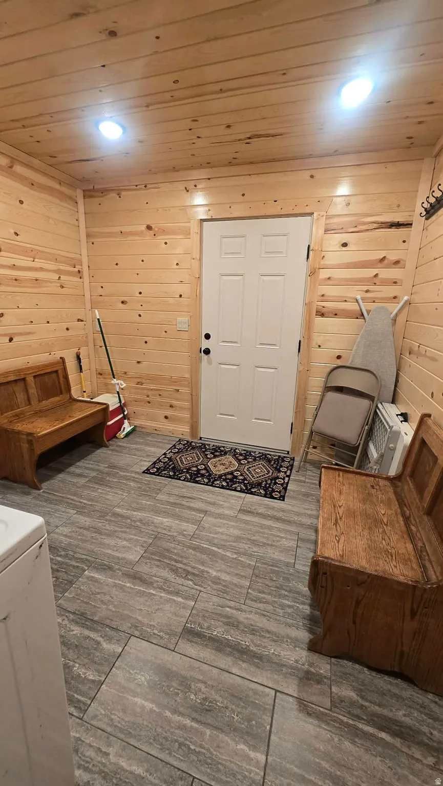 Entryway featuring wood-paneled walls and ceiling, recessed lighting, and large format gray tile flooring