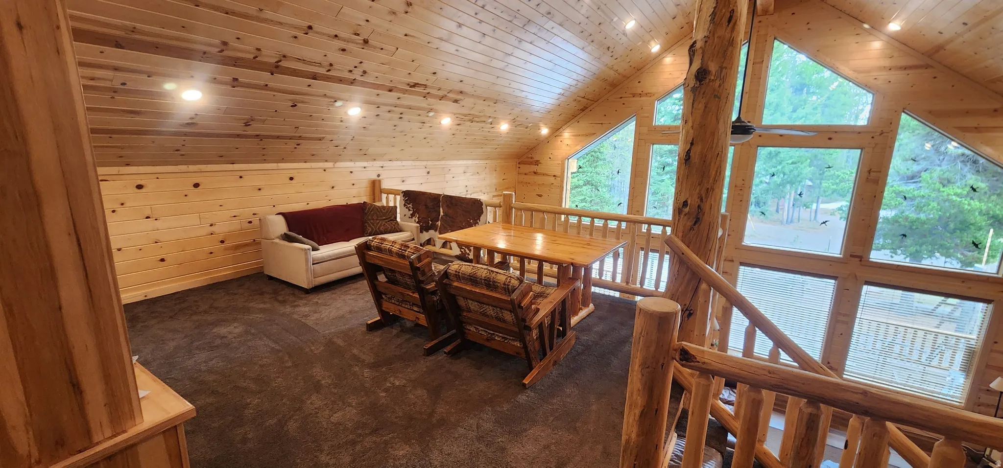 Loft area featuring sloped wood-paneled ceilings, recessed lighting, and expansive windows