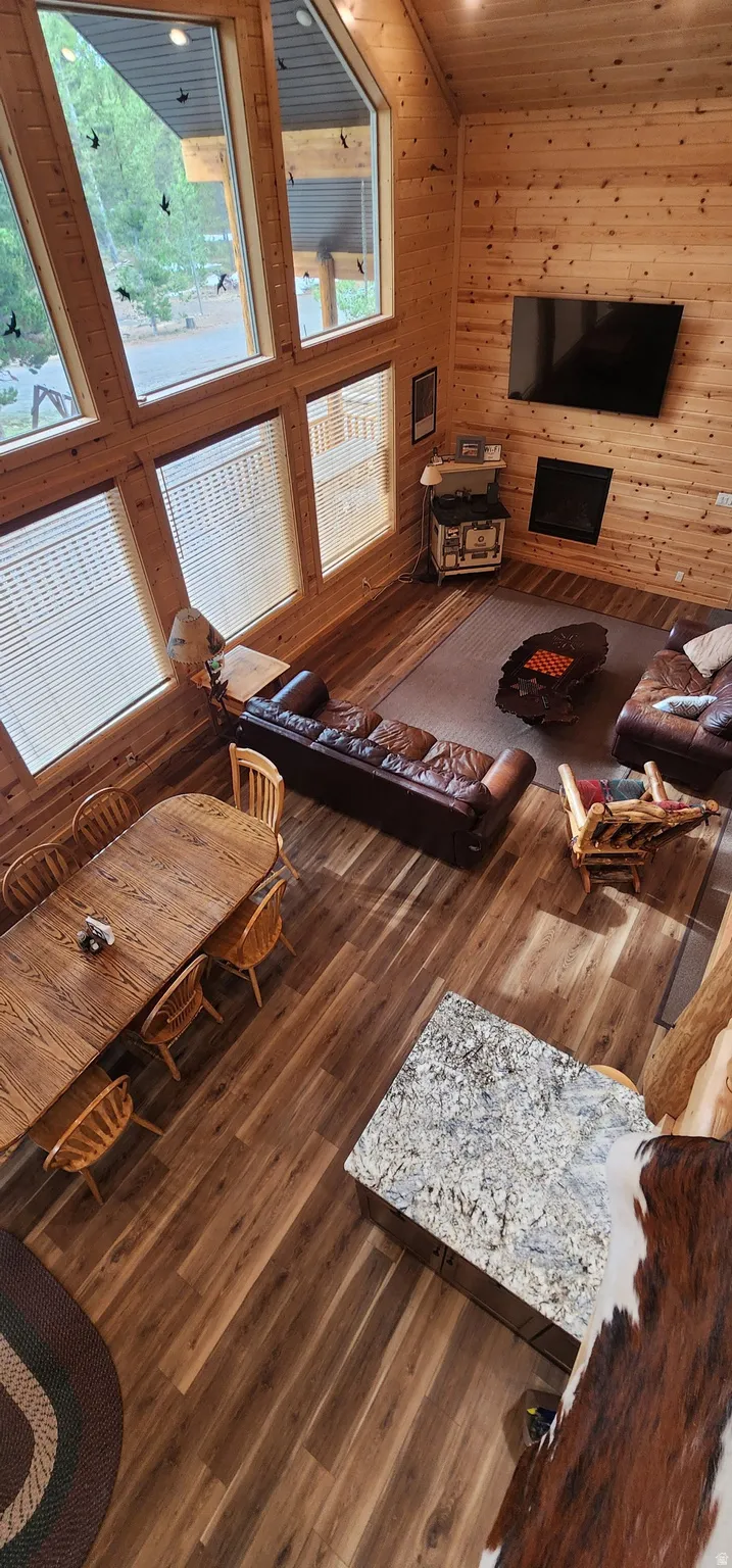 Vaulted living area featuring high ceilings, extensive wood-paneled walls, and wood-finish flooring