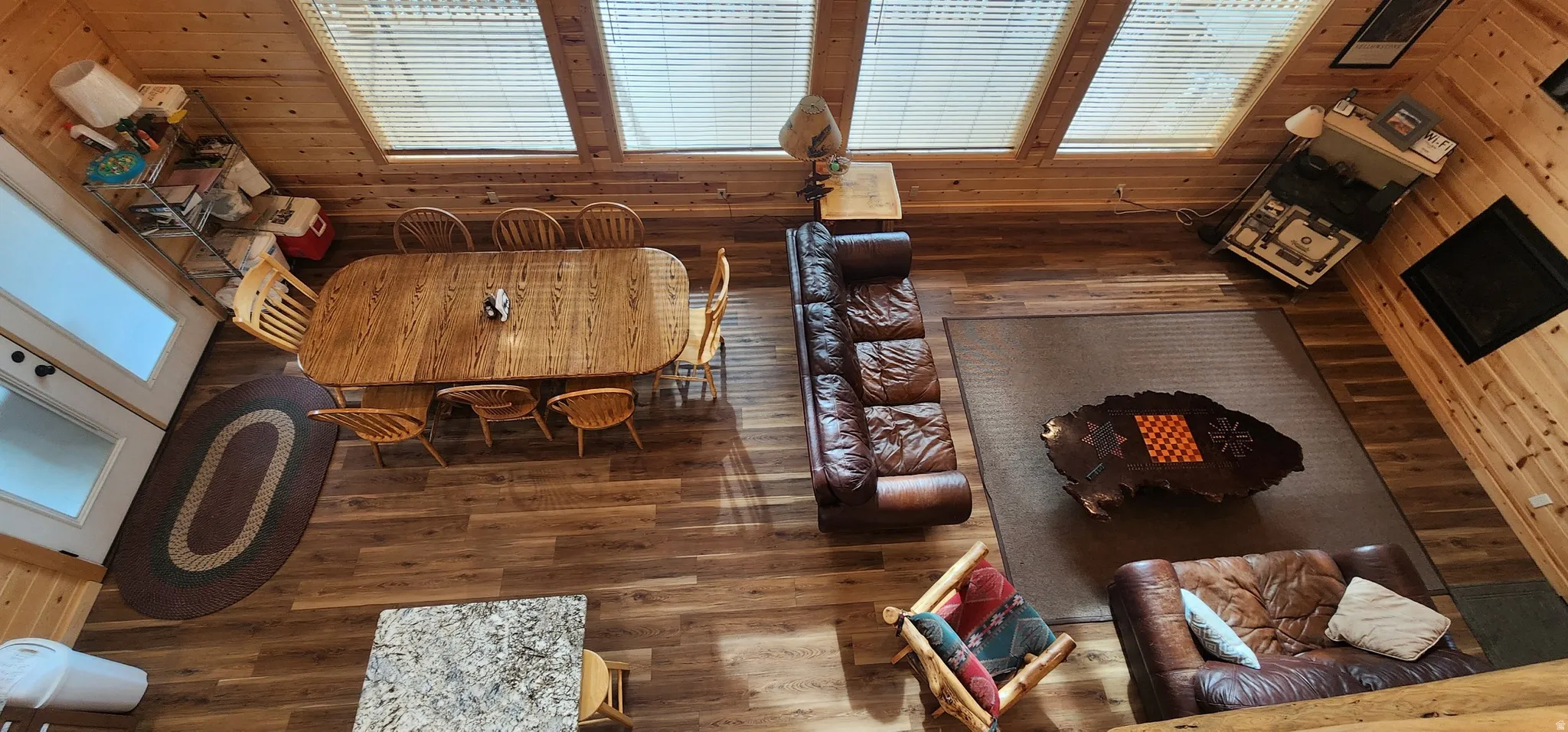 Open-concept living space featuring wood-finish flooring, high ceilings with clerestory windows, and a built-in fireplace
