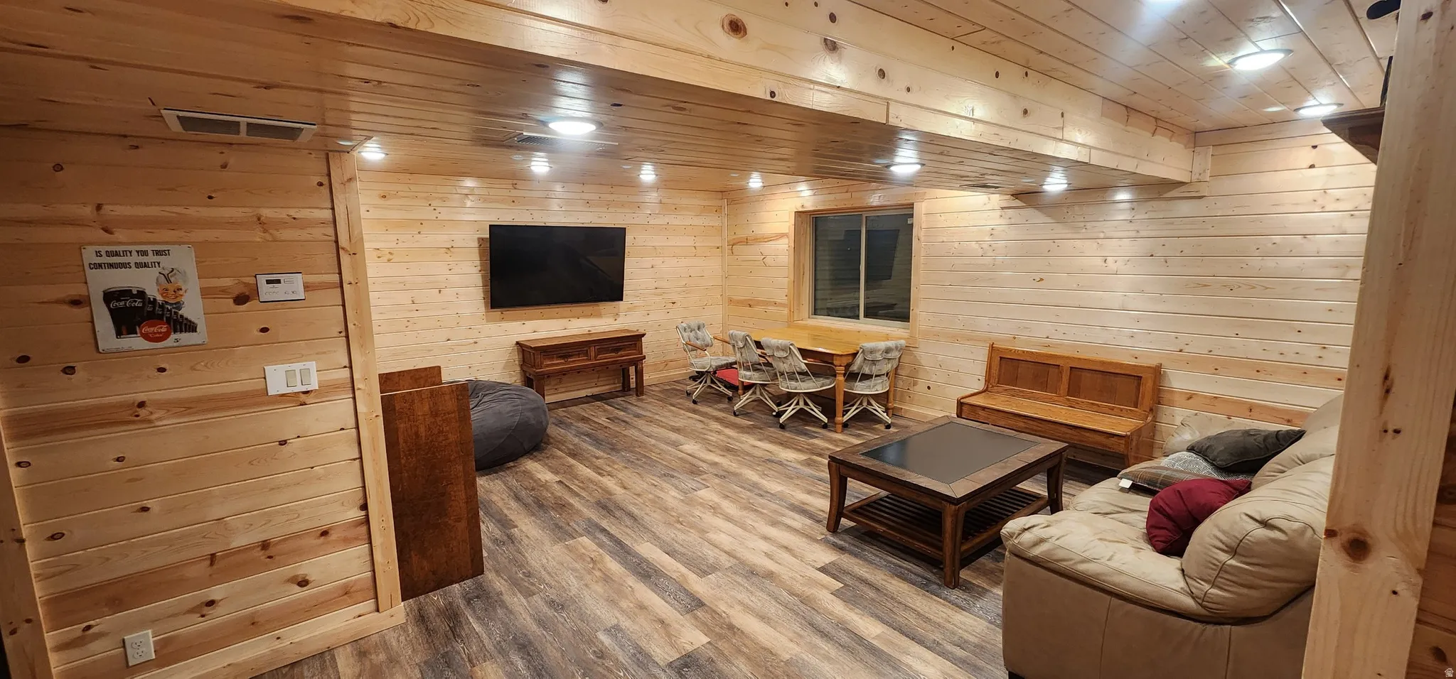 Spacious recreation room featuring plank wood walls and ceiling, wood-finish flooring, recessed lighting, and a window