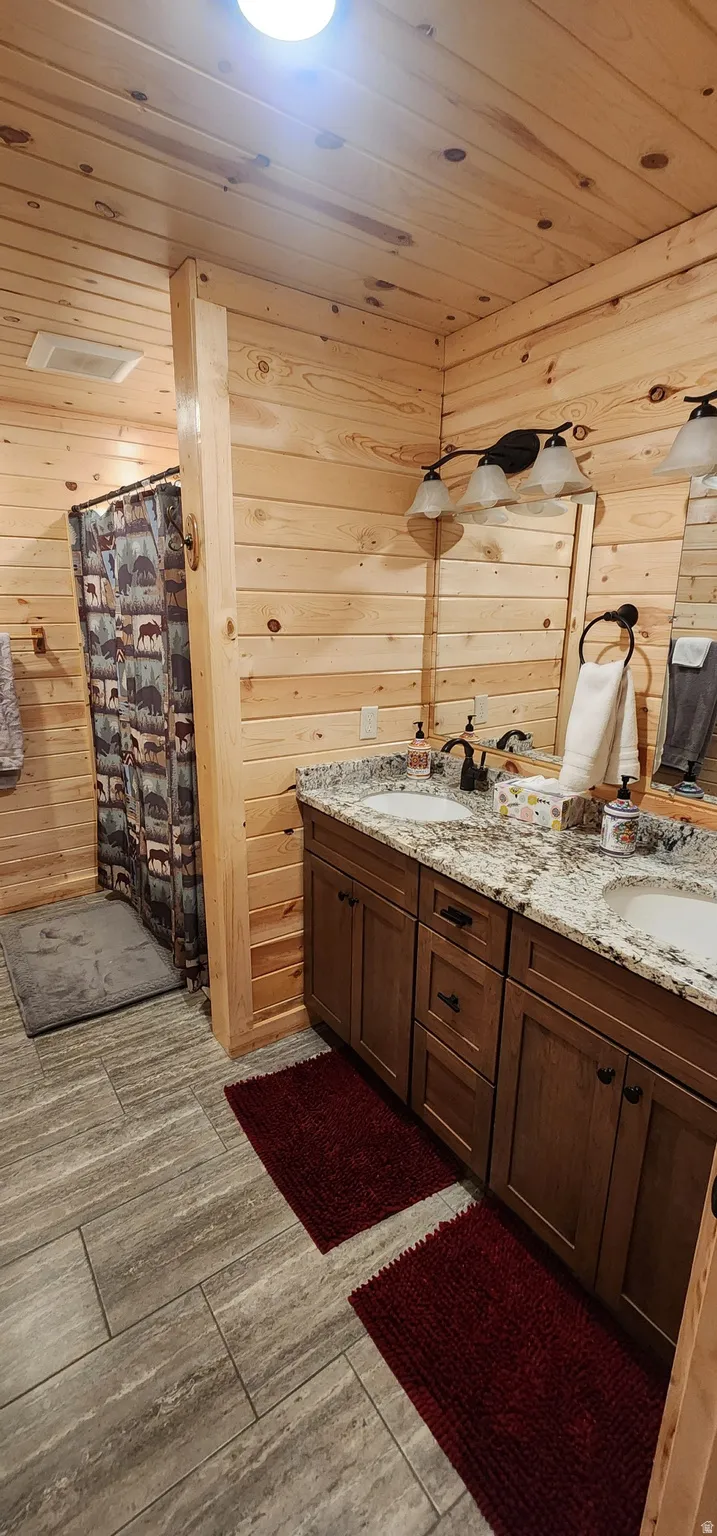 Bathroom featuring a double vanity with granite countertop, integrated sinks, and wood cabinetry