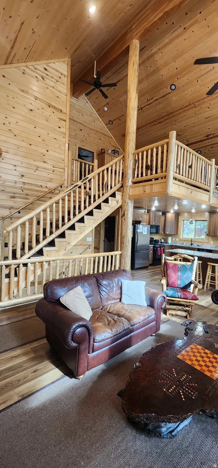 Expansive great room featuring a grand staircase with log railings, a soaring vaulted wood-paneled ceiling, and a prominent log structural column