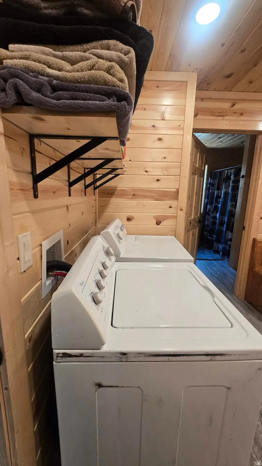 Laundry area featuring wood plank walls and ceiling, built-in shelving with black metal supports, and recessed ceiling lighting